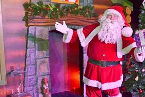 Santa in front of the fireplace holding a wrapped gift at Cadbury World